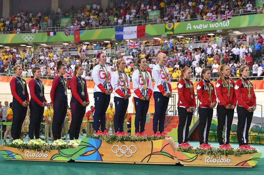 The women's team pursuit squads listen to the British national anthem