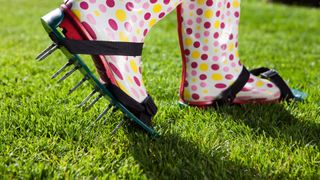 woman using aerating shoes on garden lawn