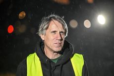 A grey haired man, Roland Bell, in a high-vis vest aqnd black hoodie in the rain