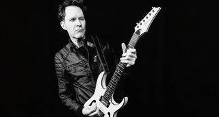 A black and white image of Paul Gilbert playing his signature Ibanez PGM301