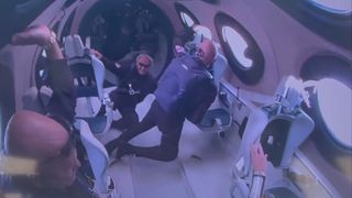 three men in dark blue flight suits float weightless inside an airplane cabin