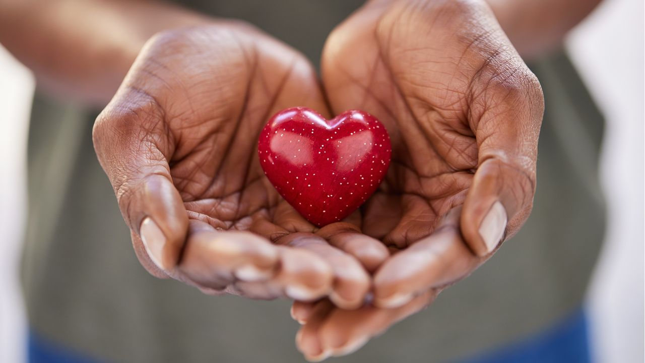 A pair of hands hold a heart knickknack.