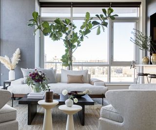 modern apartment living room with a small white couch and a collection of contemporary furniture pieces and vases of plants and foliage