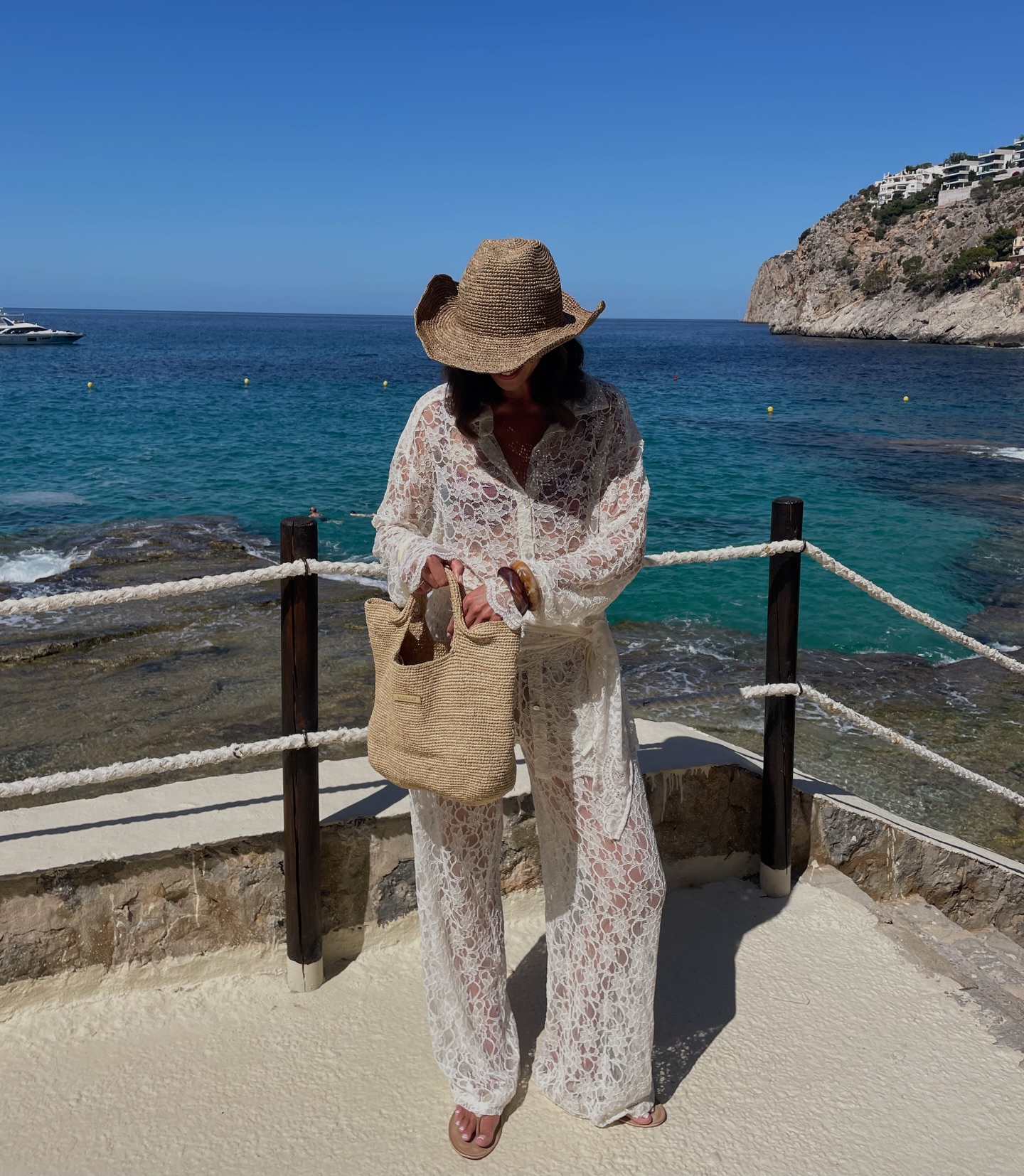 An image of elsslifestyle wearing a lace shirt with lace trousers and a raffia bag.