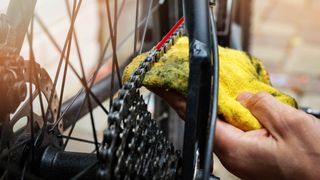 Someone cleaning a bike chain with a cloth