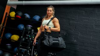 Aimee Cringle standing in gym with Built For Athletes Gym Bag over her shoulder