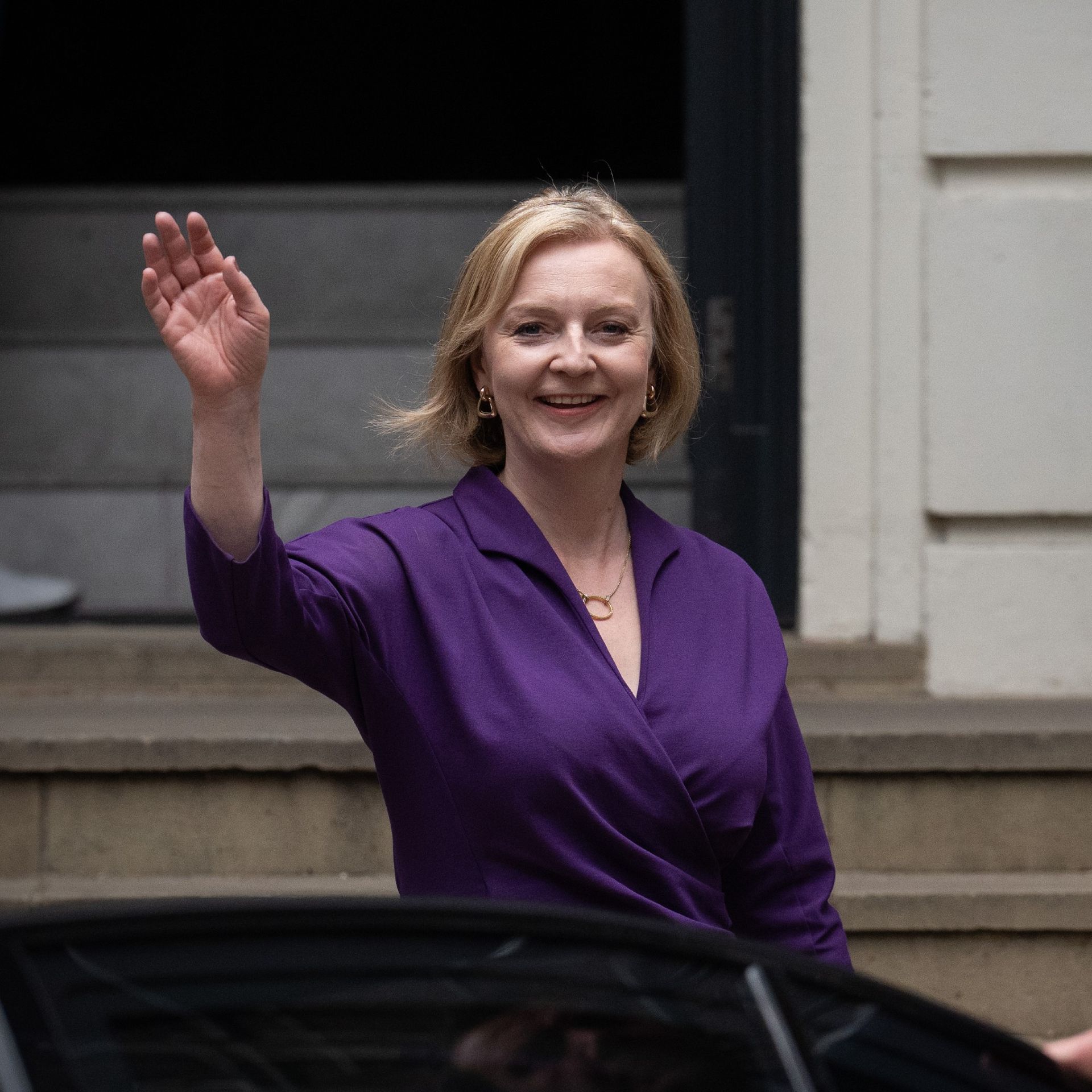Liz Truss next to car in purple dress
