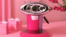 illy X7 espresso machine in pink in front of pink presents on a pink backdrop
