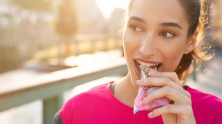 Woman eating a pre run snack: a granola bar