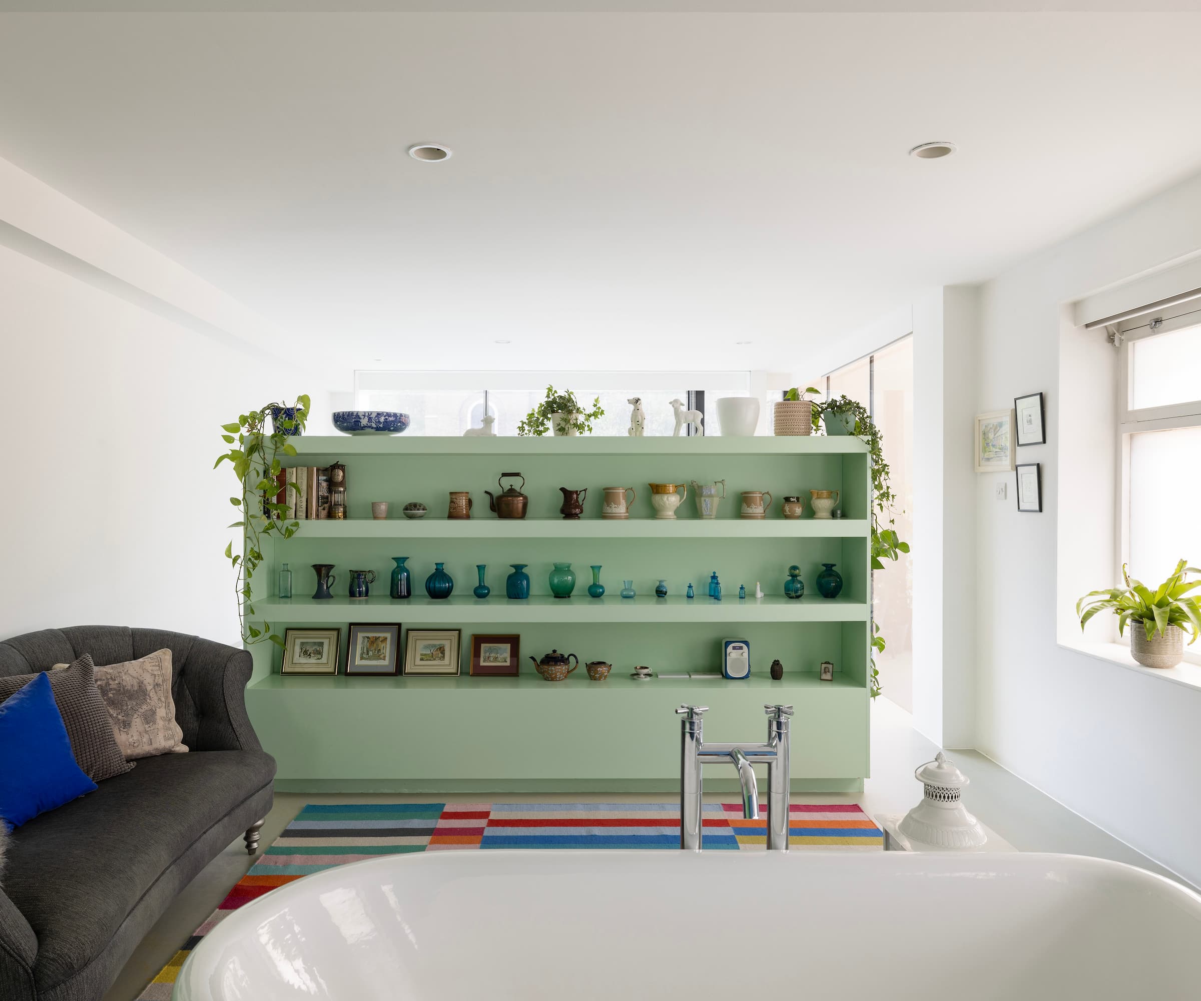 A bath with a green divider next to a sofa