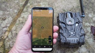 iPhone with image on the screen being held next to a Stealth Cam Fusion Global