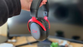 Review holding HyperX Cloud 3 Wireless against a blank monitor screen