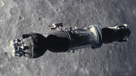 an astronaut climbs along the outside of a cylindrical spacecraft above the moon