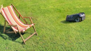 Robot lawnmower cutting grass around a deckchair
