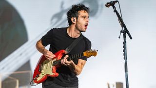The 1975's Matt Healy playing guitar on stage
