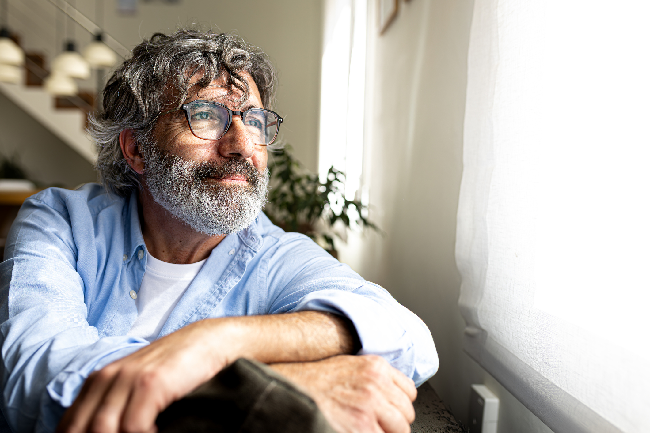 Man relaxing and looking out the window at home