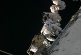 NASA astronaut Rick Mastracchio stands on the International Space Station's robotic arm during an urgent spacewalk to fix the station's vital cooling system.