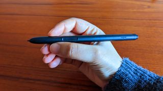 Ugee M908 review; a person holds a stylus