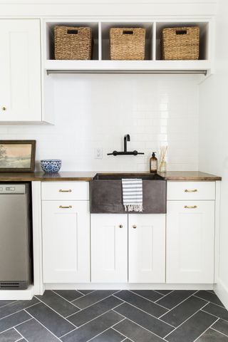 A white shelving unit with wicker baskets above a stylish grey sink