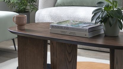 Dark wood curved coffee table with a sofa in the background 