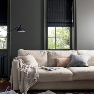 living area with black wall and black lamp and sofa with cushions