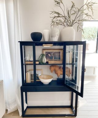 DIY vases on glass cabinet with black frame and trinkets on the shelf