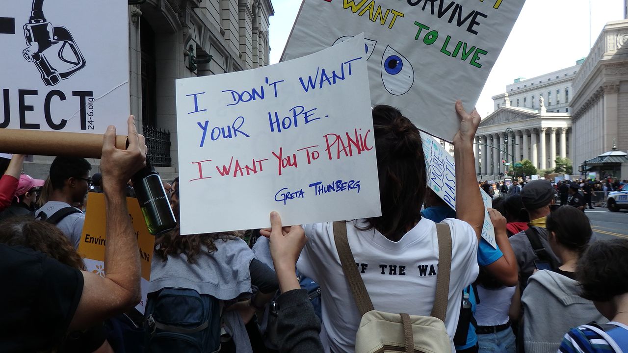 A protester holds a sign displaying a quote by Swedish teen activist Greta Thunberg: "I don't want your hope. I want you to panic."