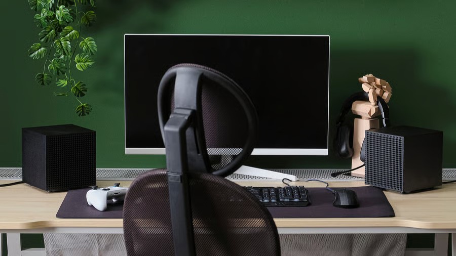 A pair of IKEA Badkruka Bluetooth speakers in black flanking a personal computer on a desk