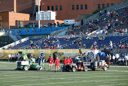 Workers on the field at the Tom Benson Hall of Fame Stadium.