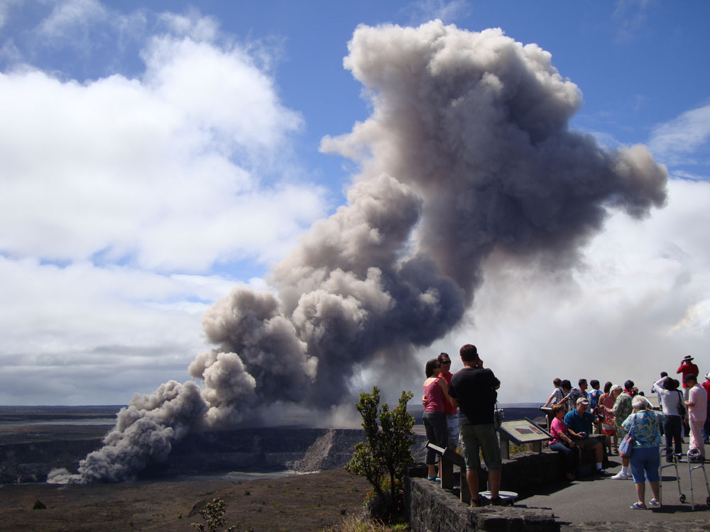 Tourists pose for photographs on 26 September 2009 less than 2 km away from the ongoing eruptive vent inside Halema`uma`u crater that spews a dark plume of gas and ash into the atmosphere above Kilauea Volcano in Hawai`i.
