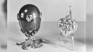 Black-and-white photo of a Faberge egg and a tiny heart on an easel.