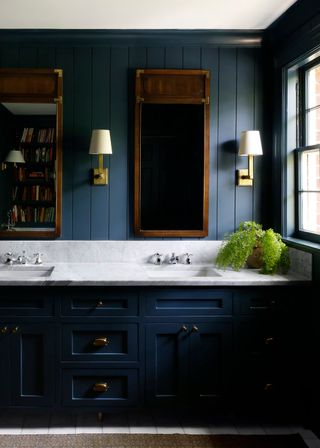 Farmhouse bathroom with navy blue walls and units, with marble sink top and brass fittings