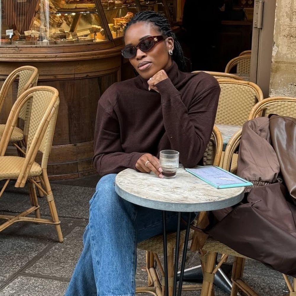 Woman wears brown sweater, blue jeans and accent jewellery