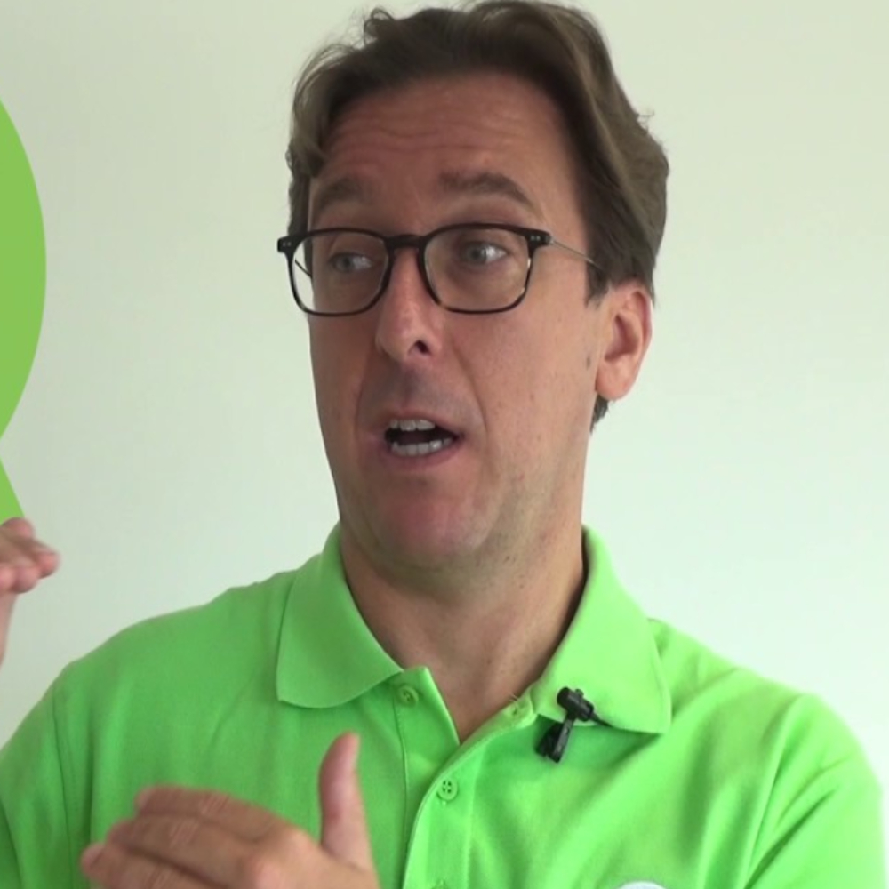 man with short brown hair wearing bright green polo shirt looking to side