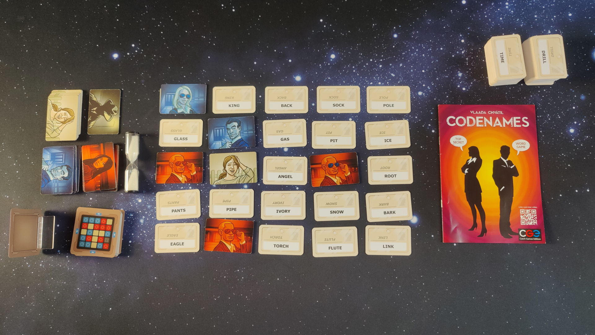 Codenames box, cards, and components laid out on a starry background