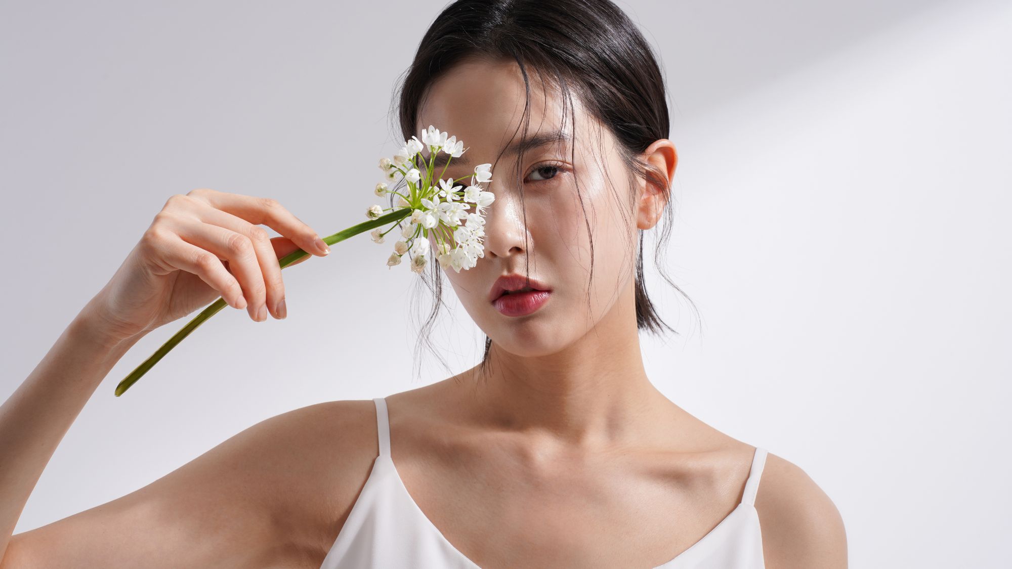An image featuring an Asian woman holding a flower