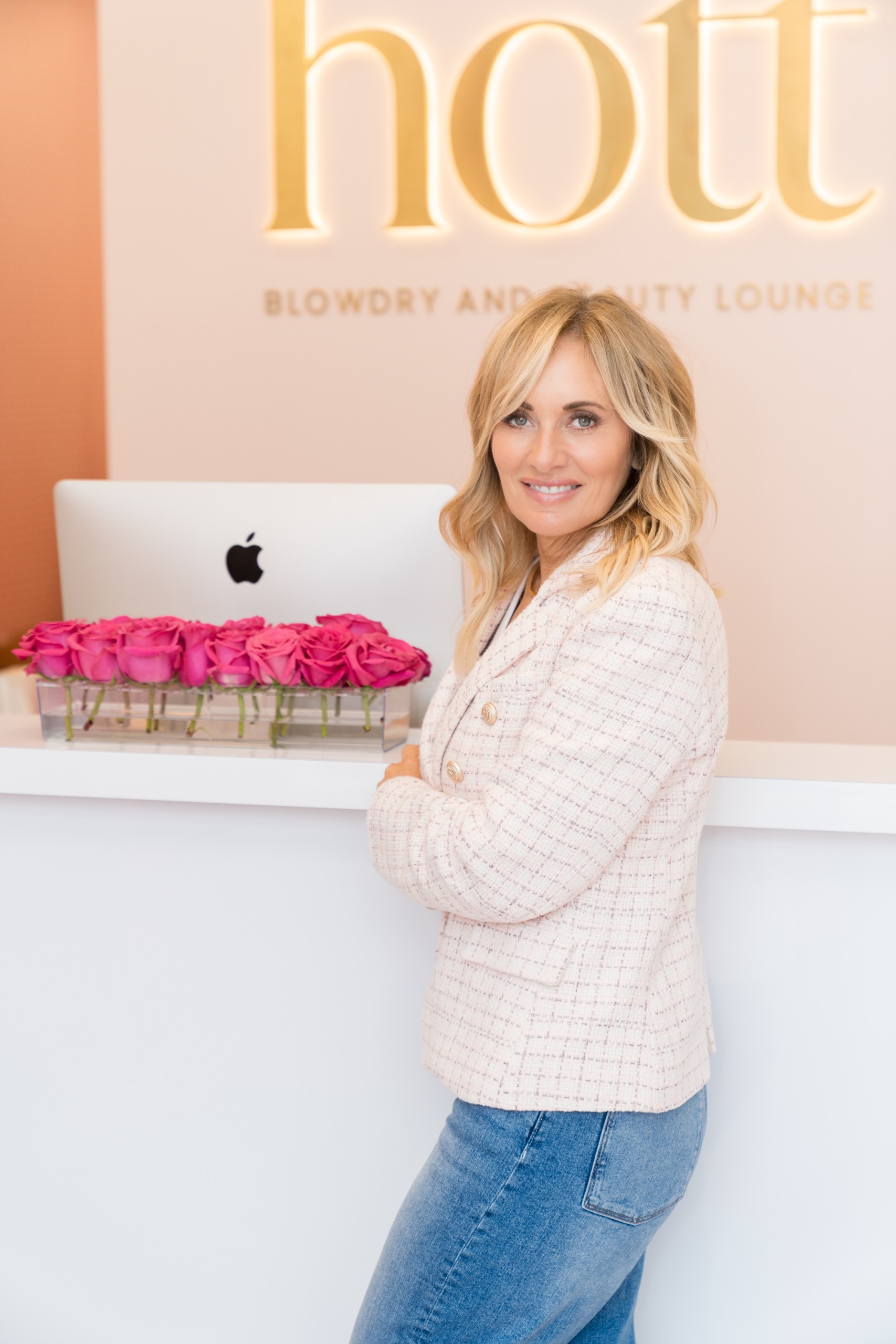a white woman with blonde hair in jeans and a pink jacket