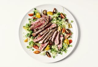 Sliced steak on a bed of salad