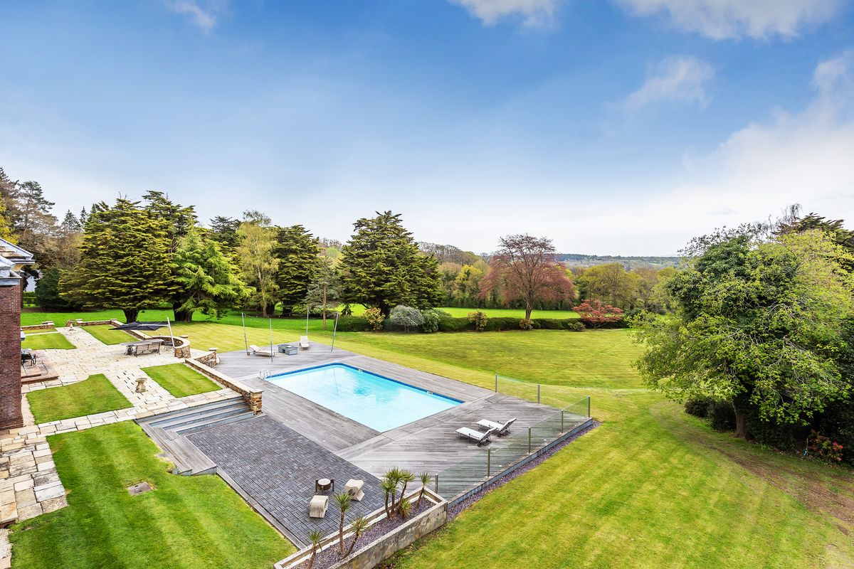A swimming pool and large open green fields