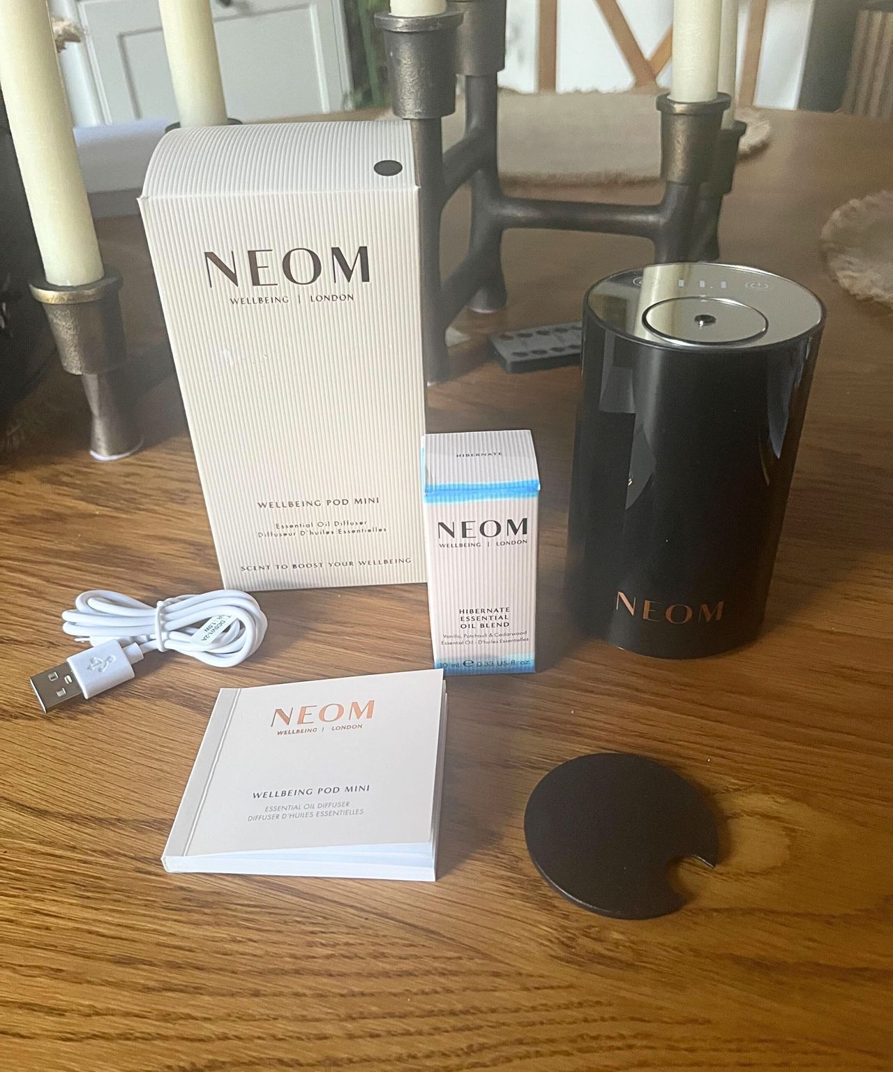 The NEOM kit - a pink box next to a black diffuser, with a manual, charging cable, and oil box