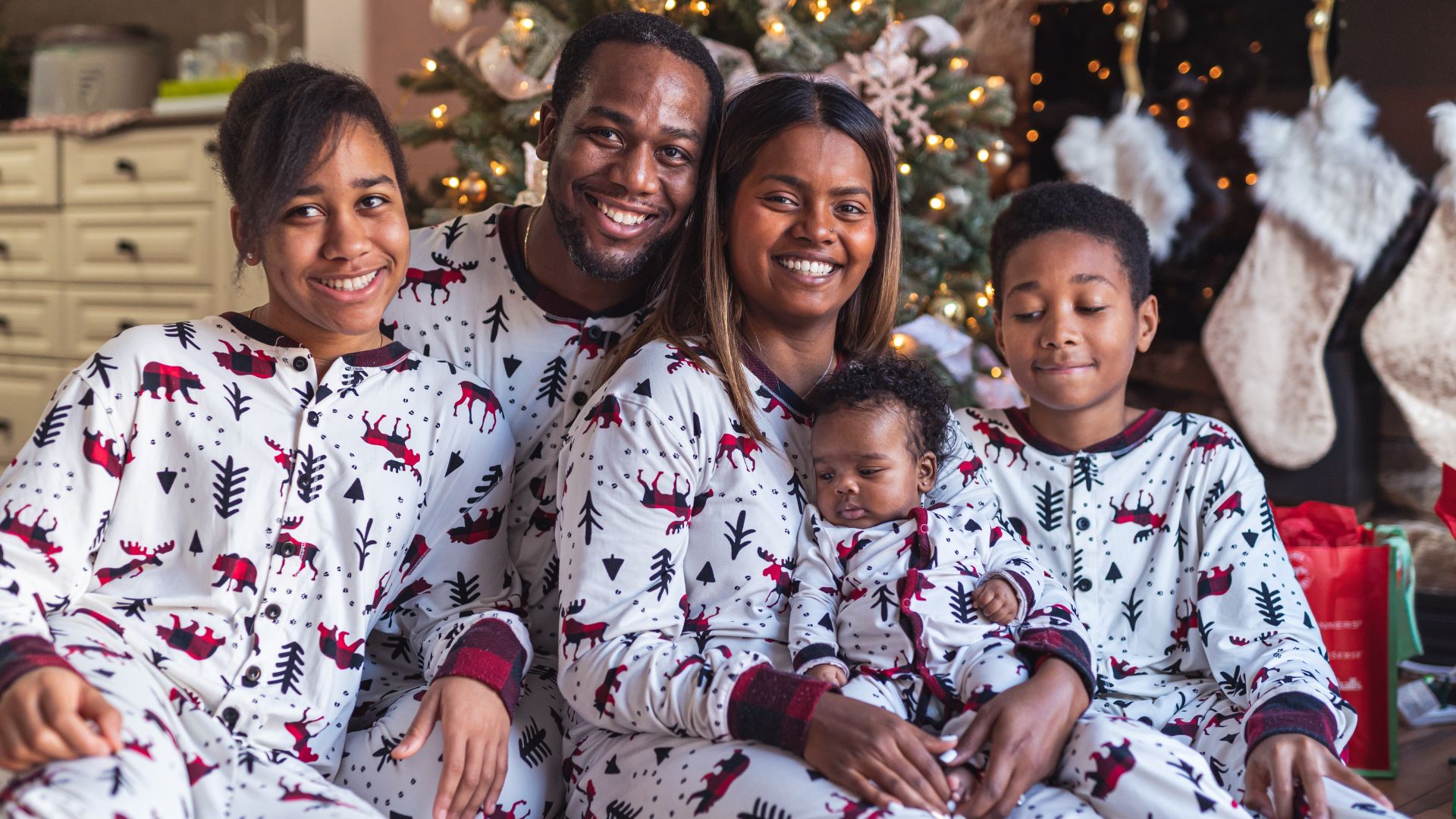 A portrait of a young family wearing matching Christmas-themed pajamas.