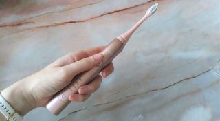 Woman's hand holding Ordo Sonic+ electric toothbrush