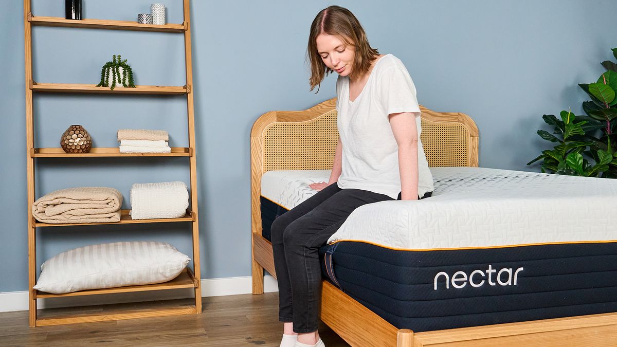 A woman sits on the side of the Nectar Ultra Hybrid mattress to test the edge support.