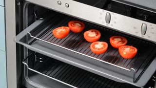 tomatoes roasting on oven rack with baking tray underneath to reduce how often should you clean your oven
