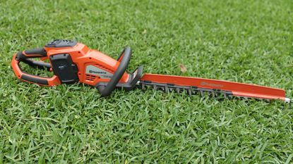 Husqvarna Hedge Master 320iHD60 laying on the lawn