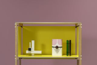 Yellow cupboard with vases on pink background