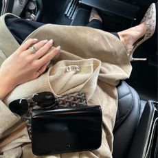 Rosie Huntington-Whiteley in the car taking a picture of her heels holding a handbag, sunglasses and a jumper in her lap