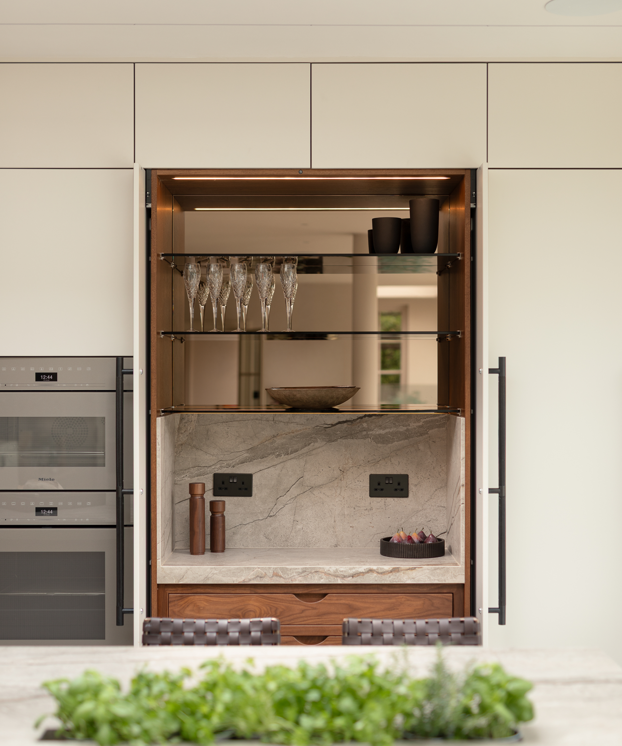 kitchen cabinets open to show shelving with glasses and preparation area below