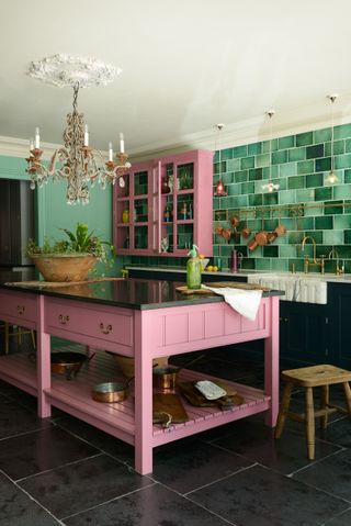 kitchen with a pink kitchen island and green splashback tiles