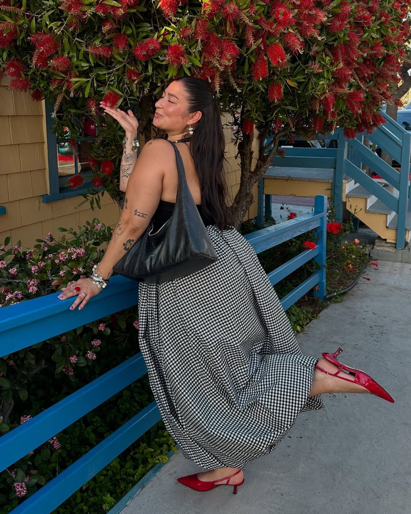 @javiera wears cherry red slingback heels with a black halter top, black and white gingham skirt and black leather tote.